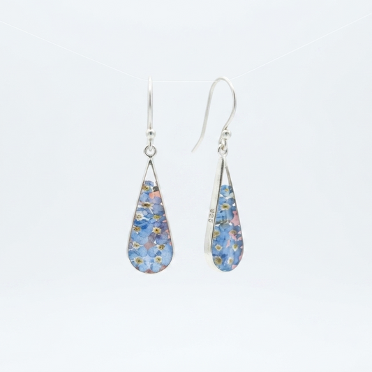 A pair of silver teardrop dangle earrings with blue forgetmenot flowers dried inside the teardrop, shown against a plain white background.