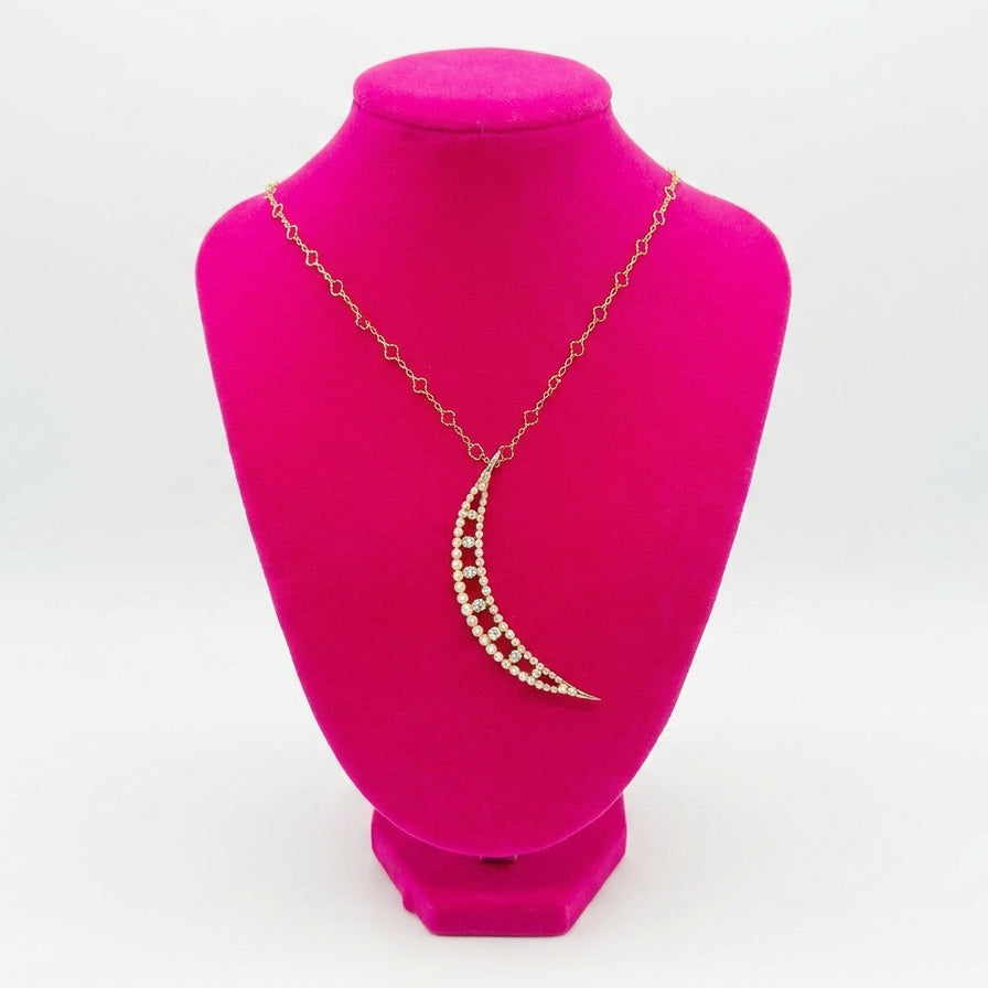 Crescent moon pearl and diamond necklace on a pink mannequin bust with a white background