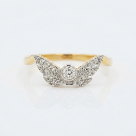 A vintage-style wing-shaped ring featuring a yellow gold band and a pavé-set diamond center with a round diamond, photographed on a clean white background.