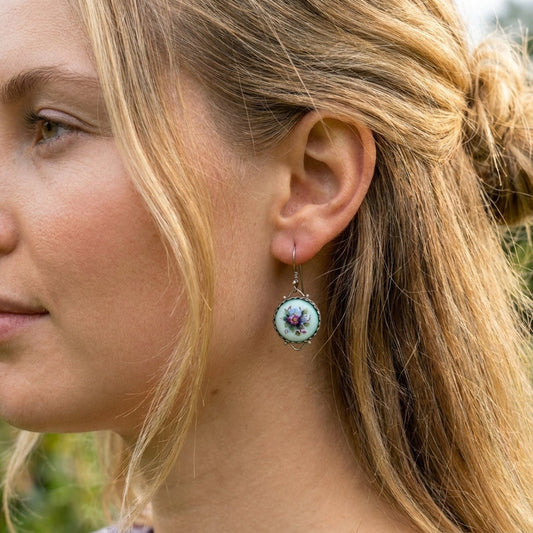 Close-up of a woman wearing earrings with a blurred natural background